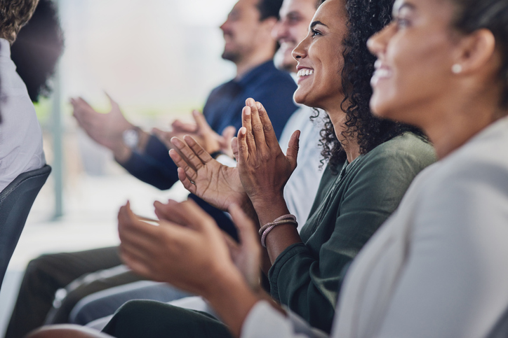 grupo de pessoas diversas sentadas, aplaudindo e comemorando uma conquista da empres