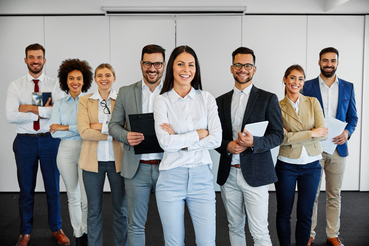 grupo diverso de funcionários de empresa sorrindo lado a lado, demonstrando confiança e otimismo.